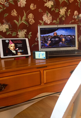 Electronic devices on table with red floral wallpaper in background