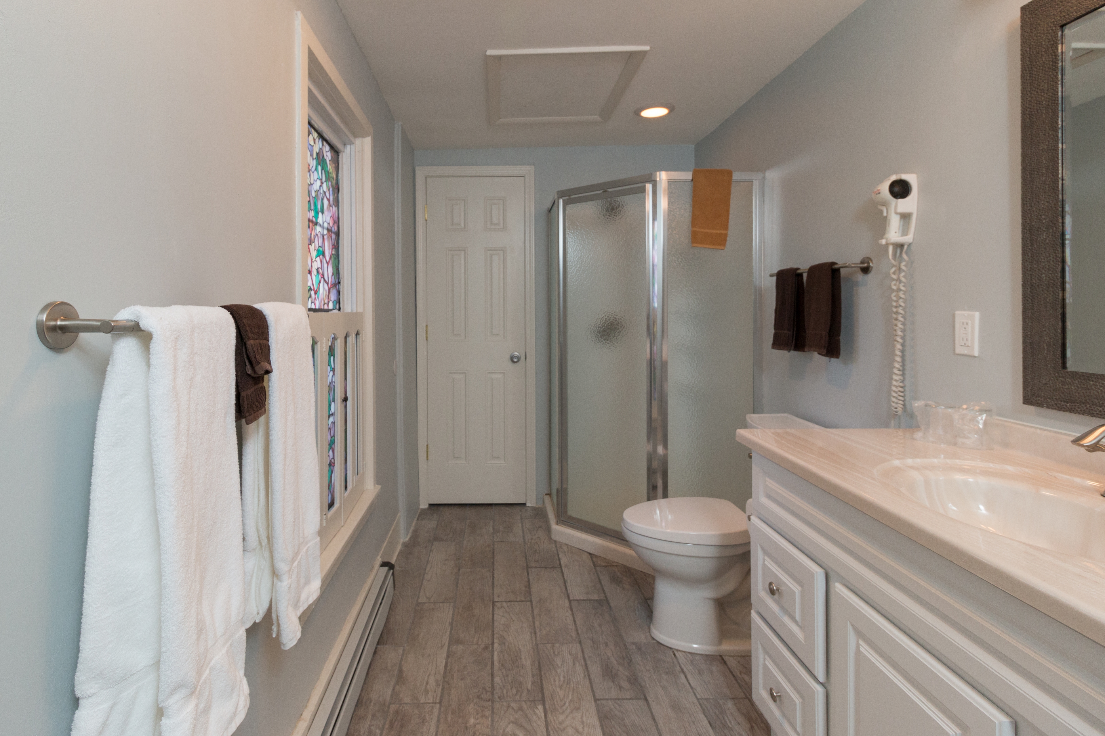 Galley style bathroom with long vanity, stool, and walk-in shower