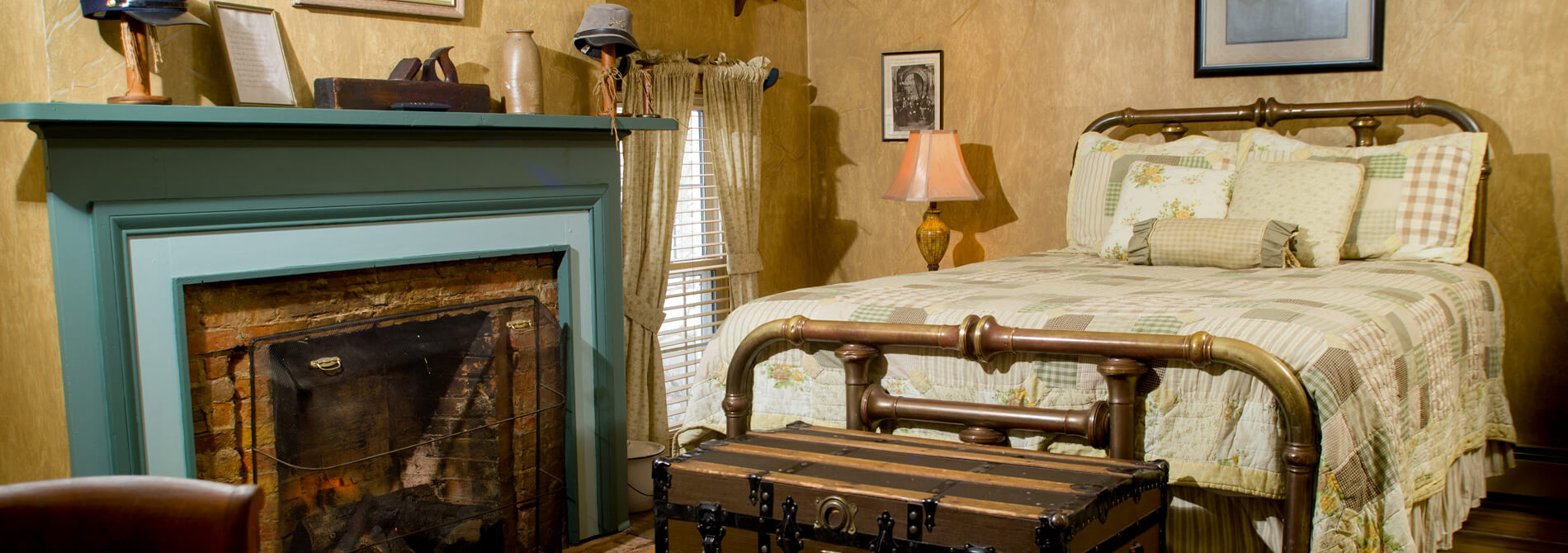 Patchwork quilt on brass bed with green facade fireplace