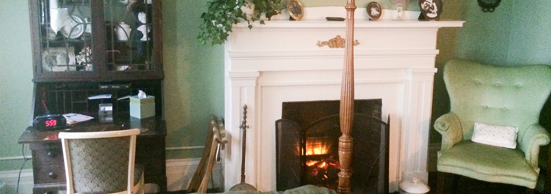 White facade fireplace in green bedroom