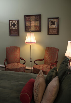 Floor lamp flanked by red chairs with artwork on wall above