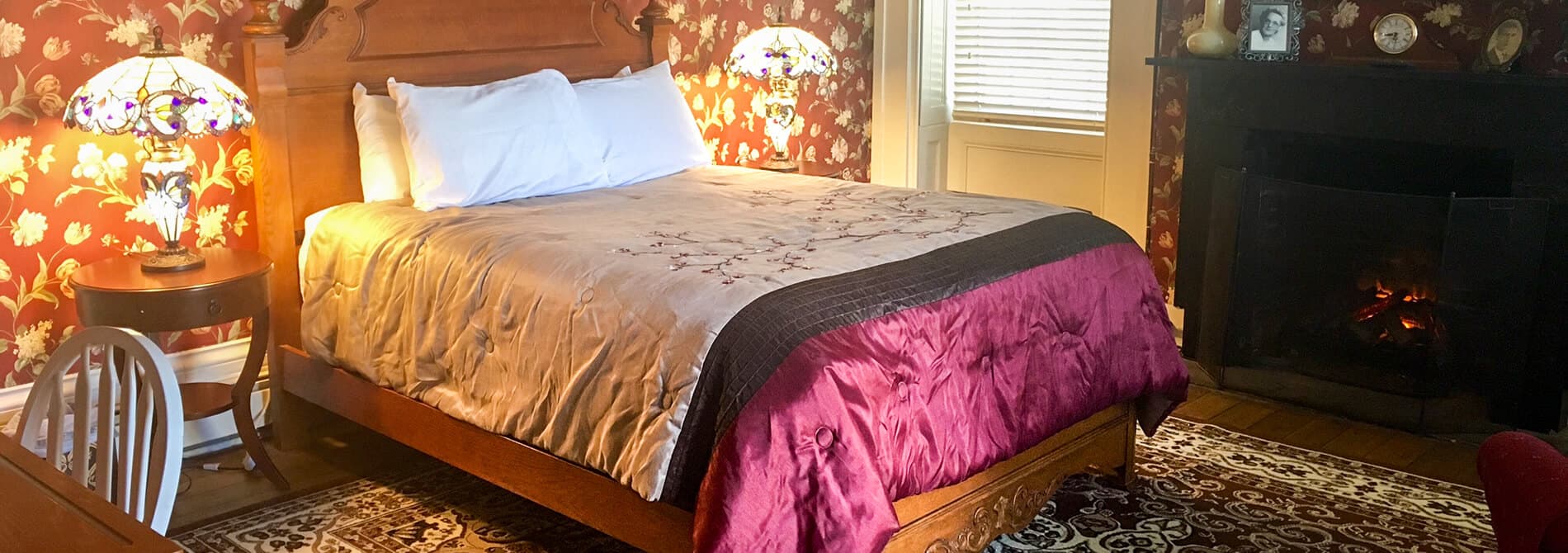 Mansion bed with brown and maroon quilt flanked by Tiffany style lamps on night stands
