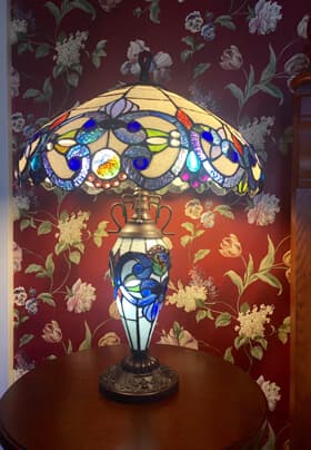 Multicolored Tiffany lamp against red floral wallpaper