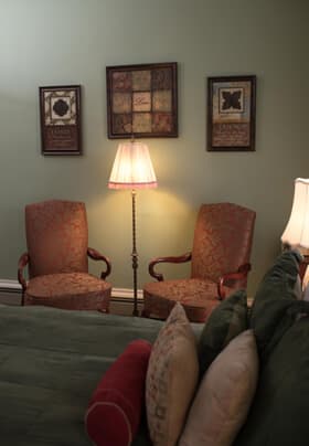 Floor lamp flanked by red chairs with artwork on wall above