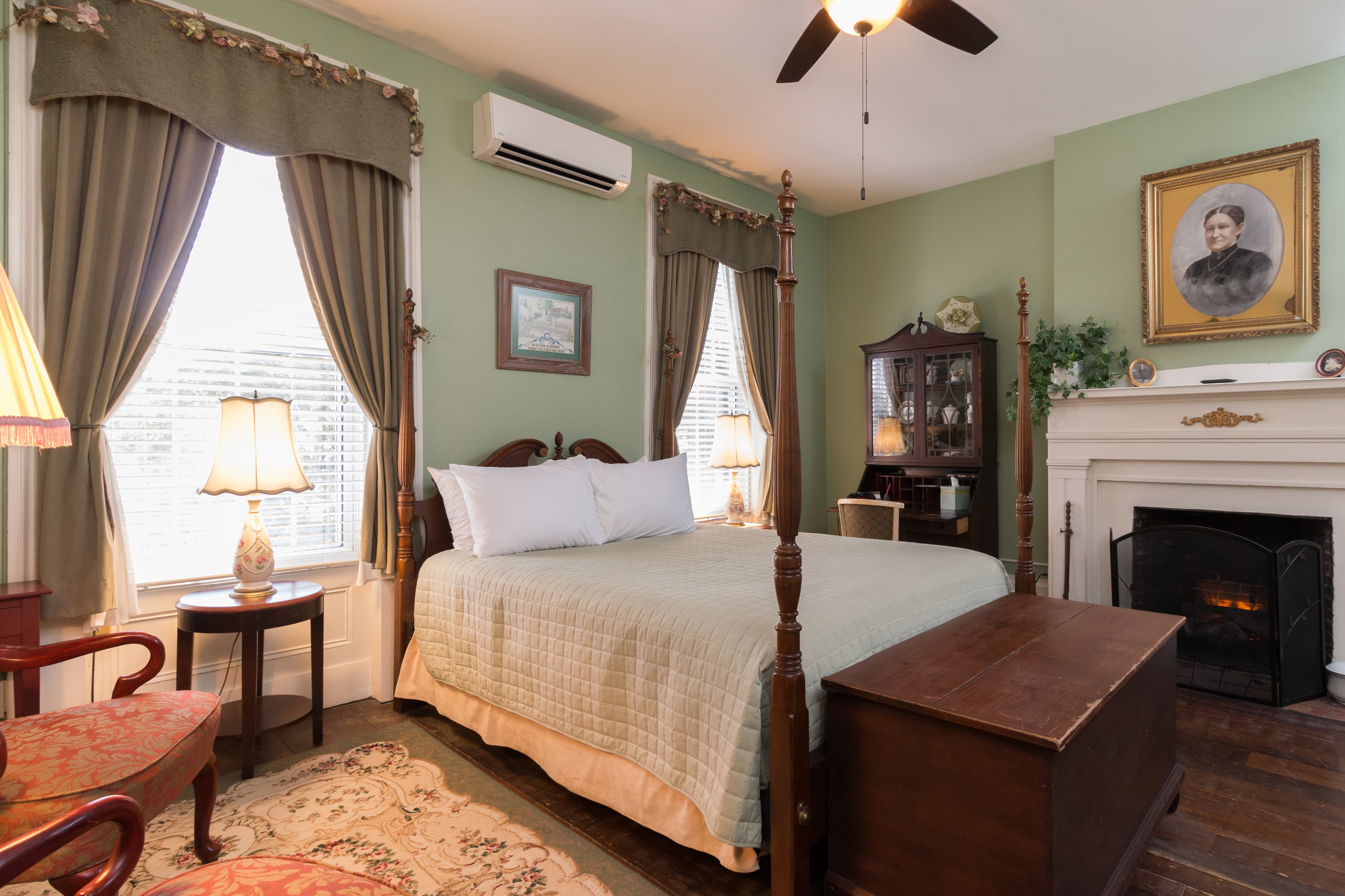 Romantic bedroom with 4 poster bed 2 windows and a white mantel fireplace