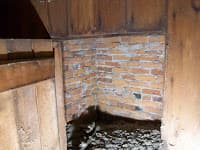 Interior corner of a building showing exposed brick and wooden structure.