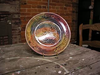 A decorative plate with swirling patterns and the words "Peace," "Hope," and "Happiness" etched around the edge.