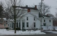 A white house with multiple gables and a snowy yard.