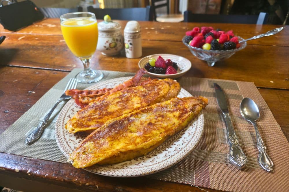 A plate of two golden omelets, crispy bacon, and a side of fresh berries, accompanied by a glass of orange juice.