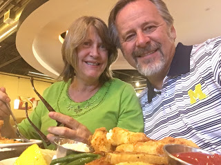 White couple in seafood restaurant, woman in green shirt, man in striped Michigan Logo shirt