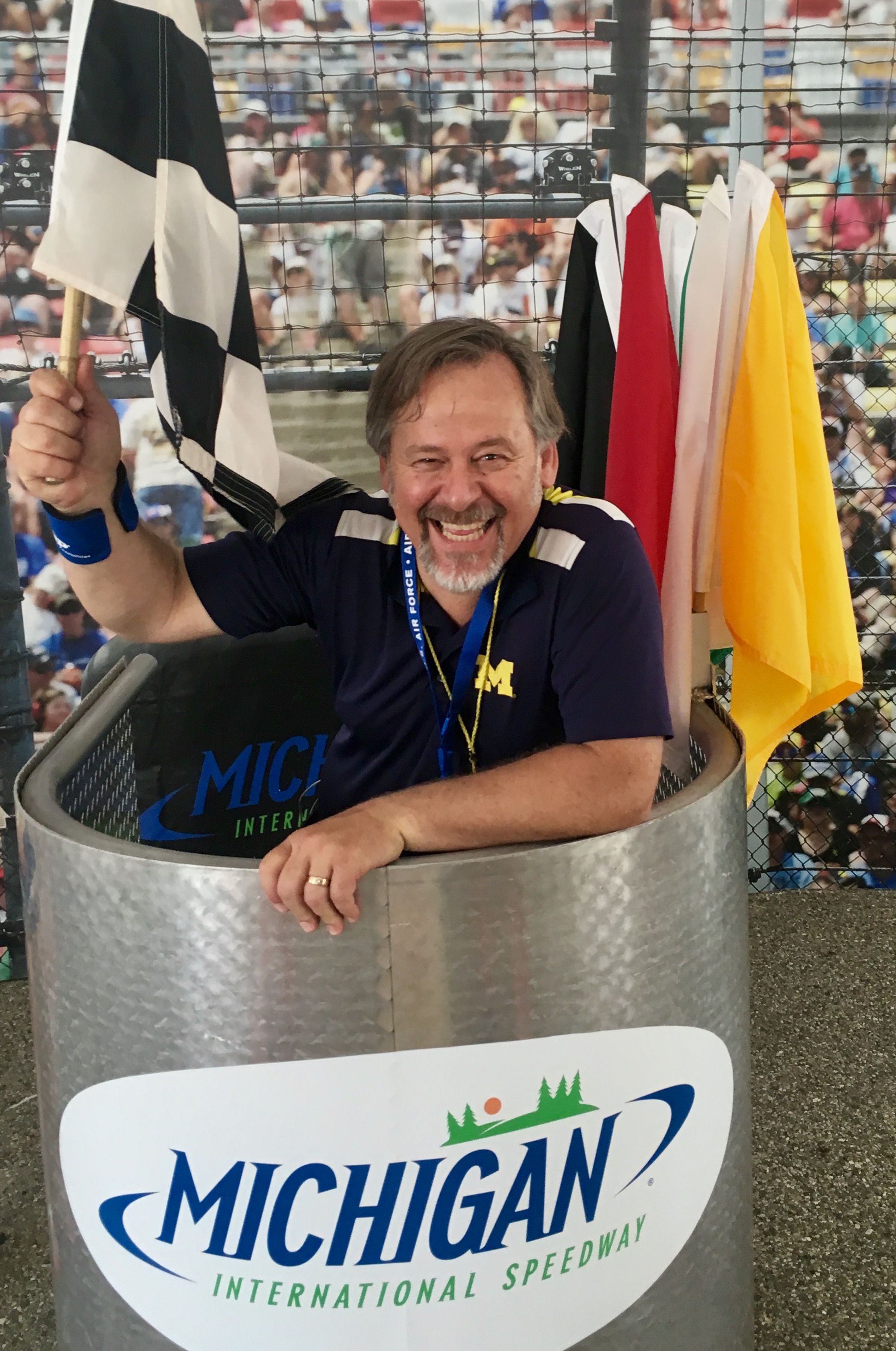 man in a blue shirt holding a checkered flag while standing in a michigan international speedway booth